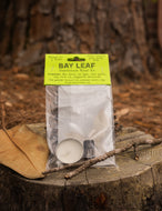 Packaged bay leaves with a candle on a wooden stump outdoors